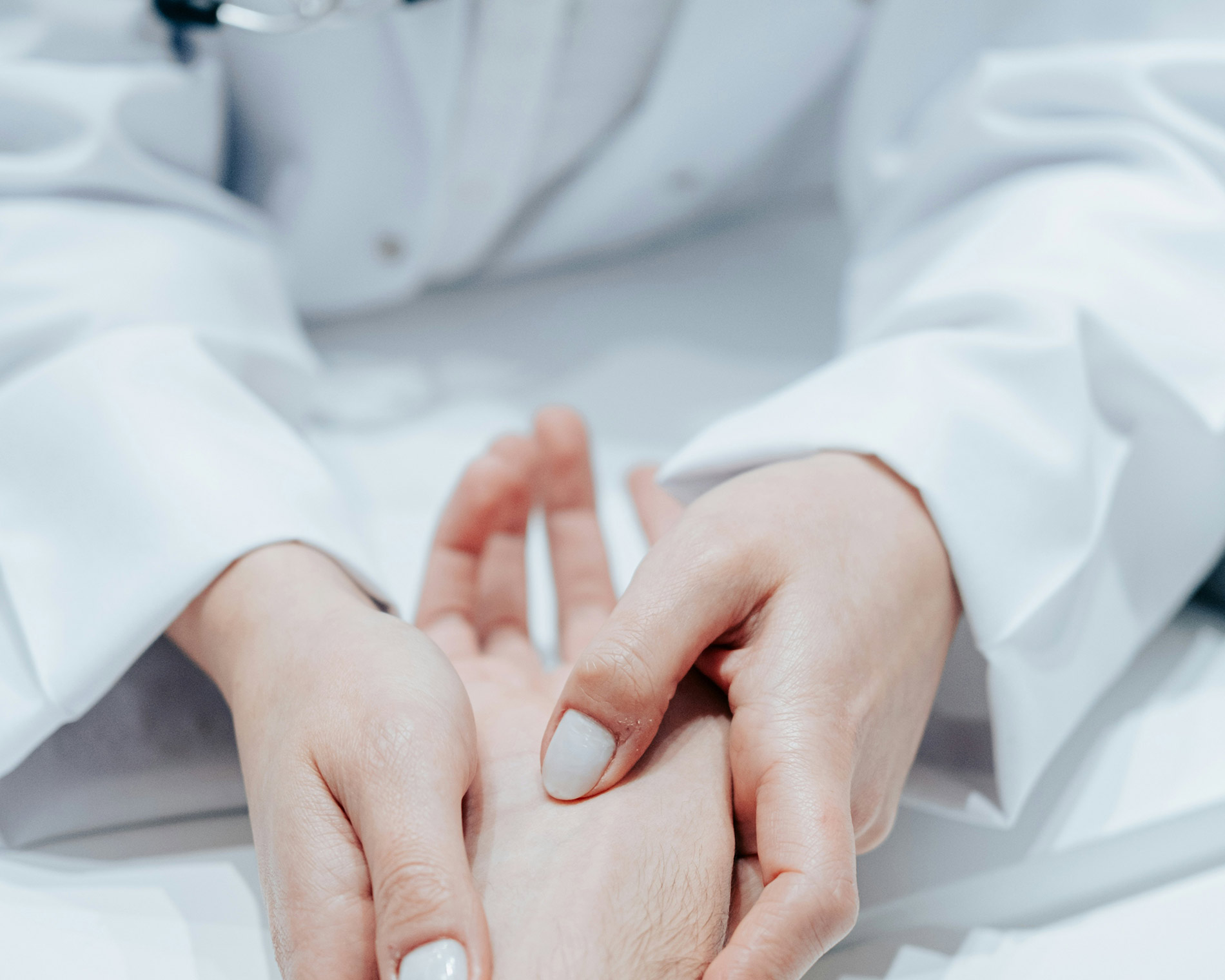 Arzt tastet Hand einer Patientin ab 